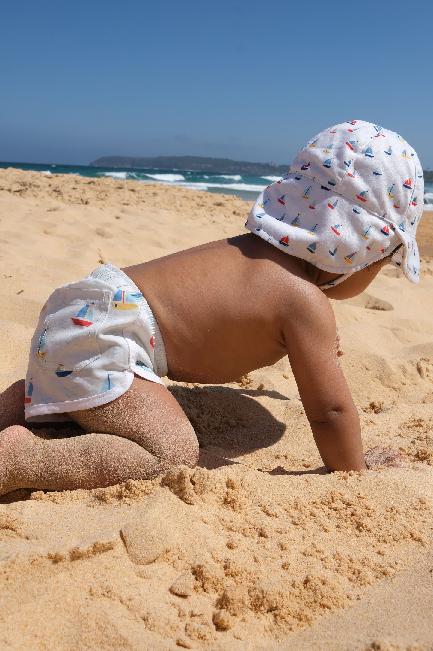 baby wearing boardshorts at the beach