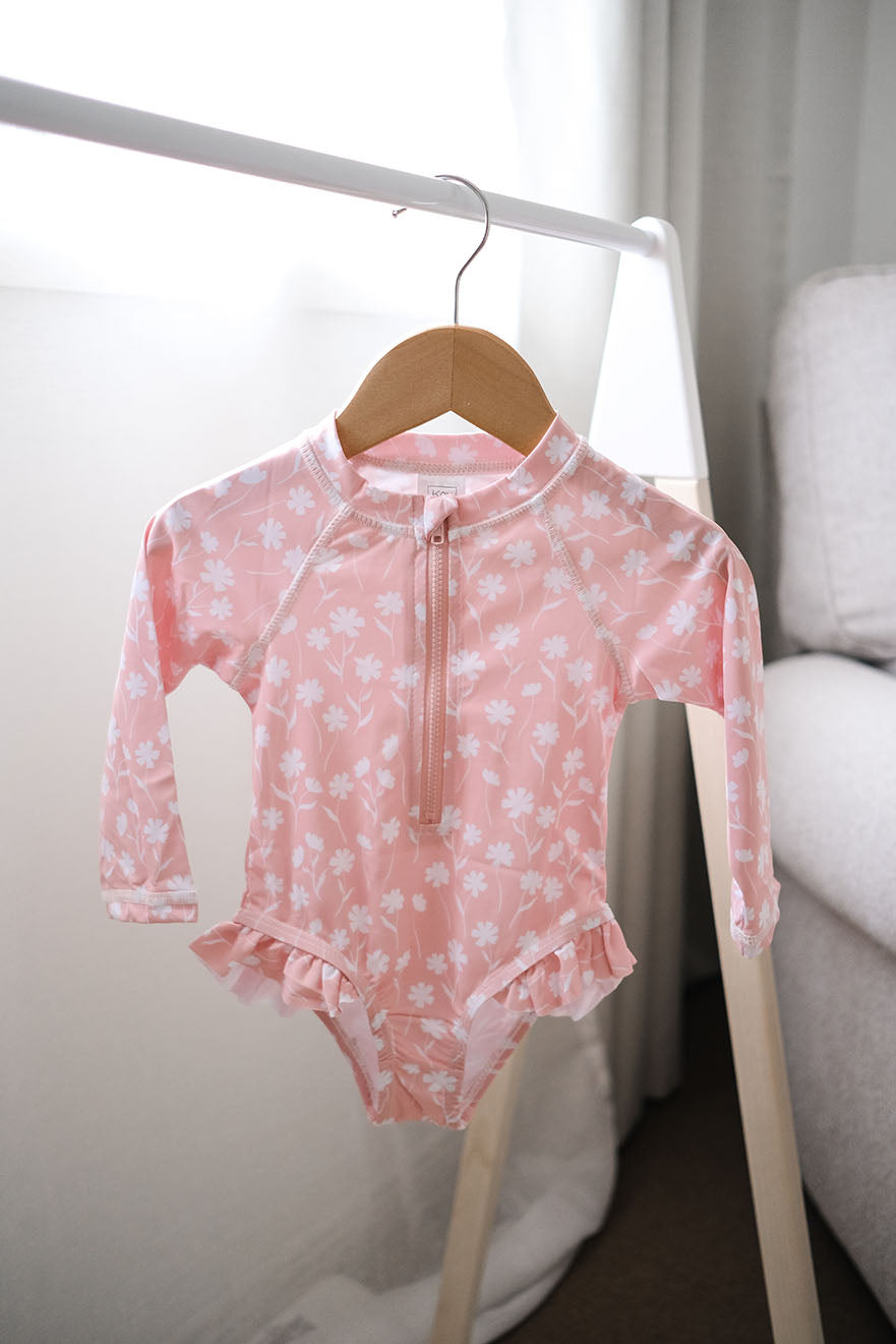 Baby girls one piece long sleeve swimsuit in pink floral design.