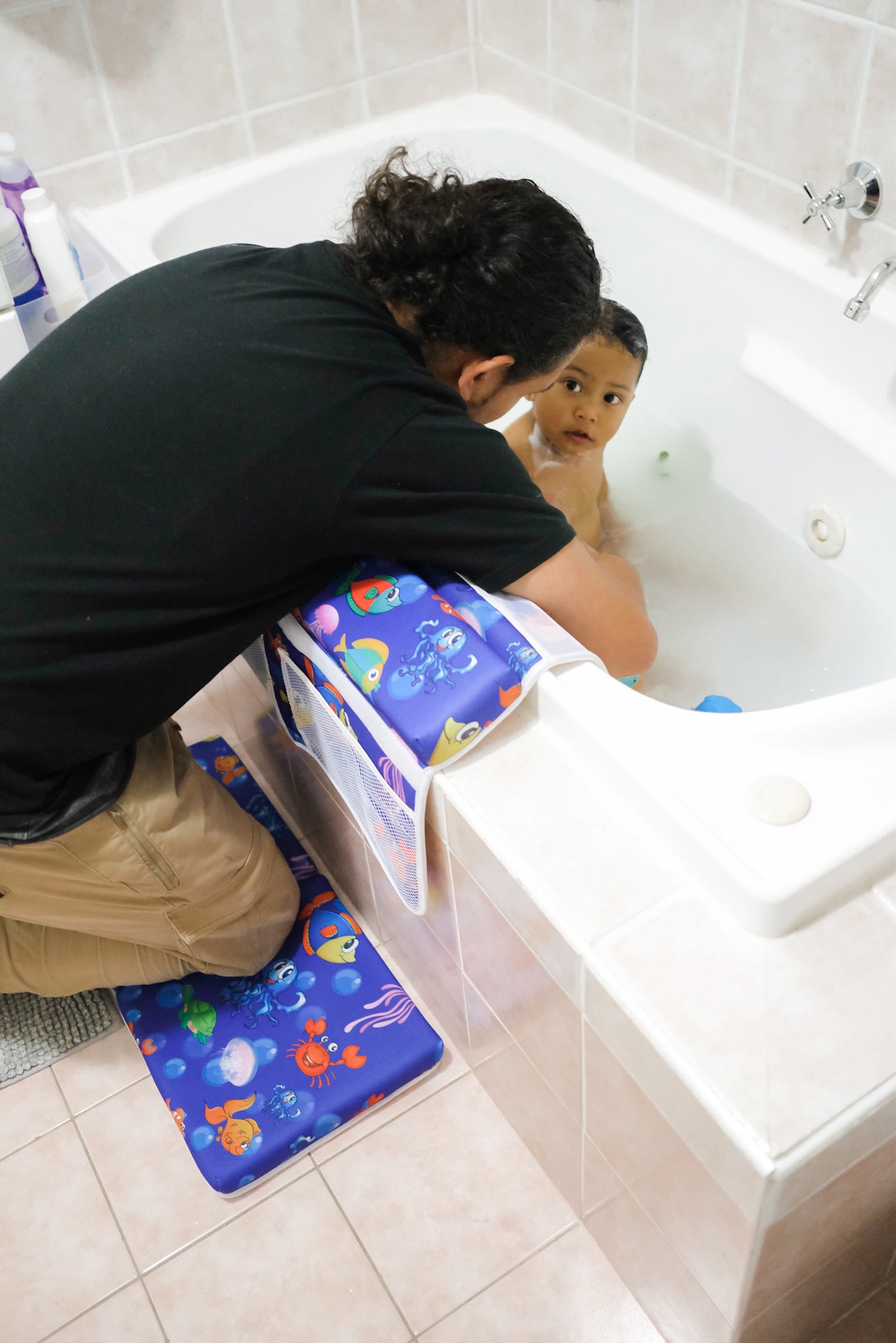 Father giving his son a bath while using baby kneeler and elbow pads to protect his knee and elbows