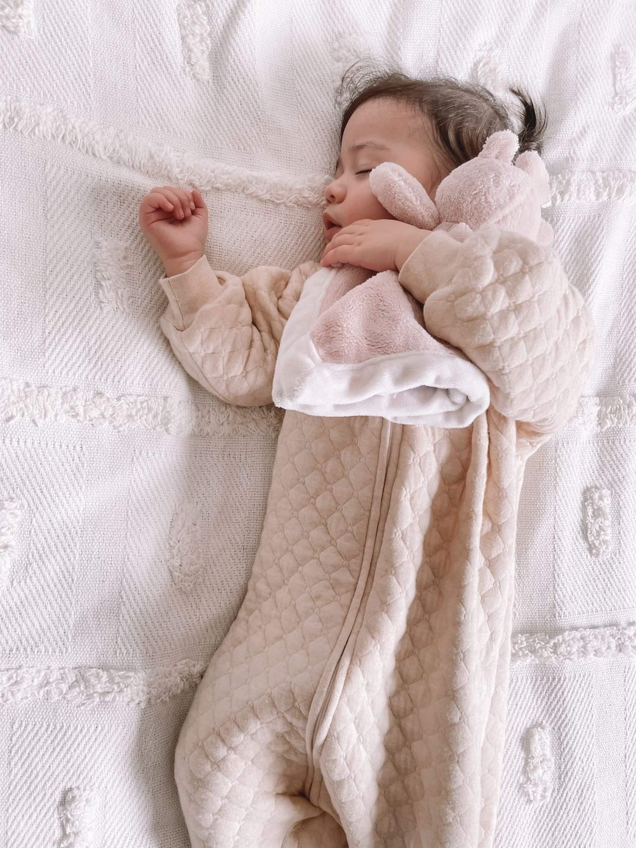 baby girl sleeping wearing a 1.0 tog sleep suit