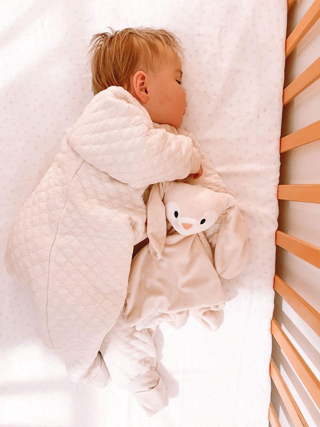 Baby wearing quilted 1.0 tog sleepsuit sleeping in a cot