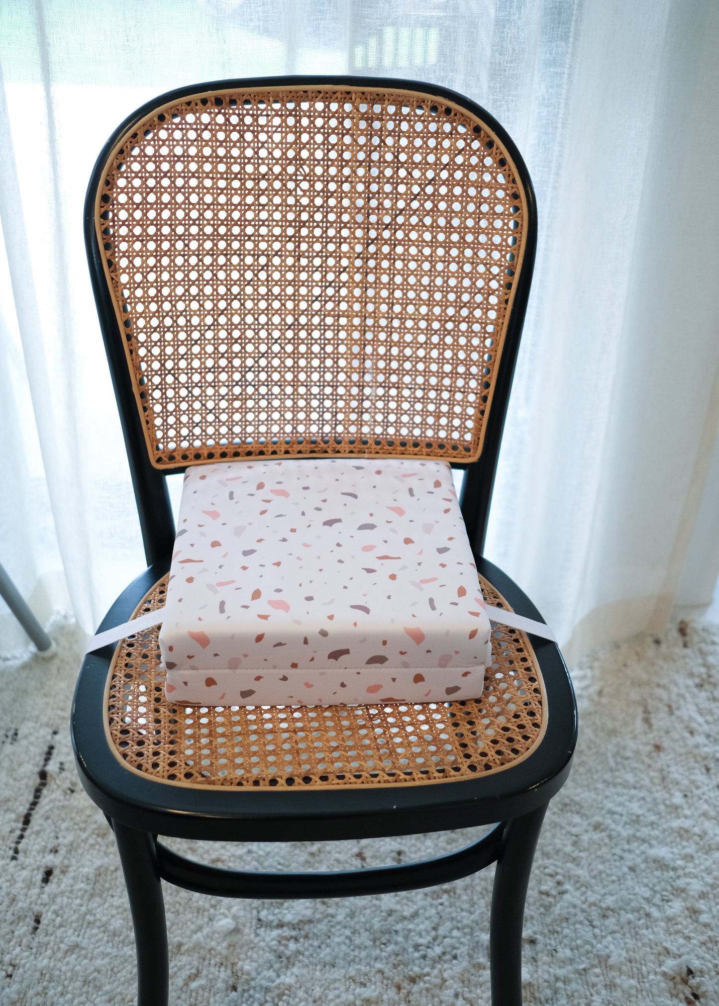 Kids booster seat on dining chair with terrazzo pattern