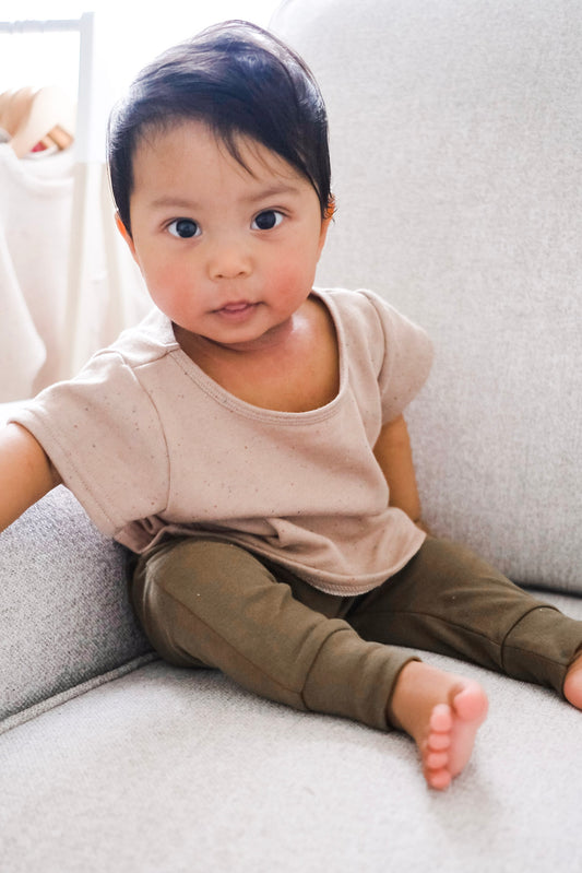 Baby wearing khaki leggings sitting on a chair