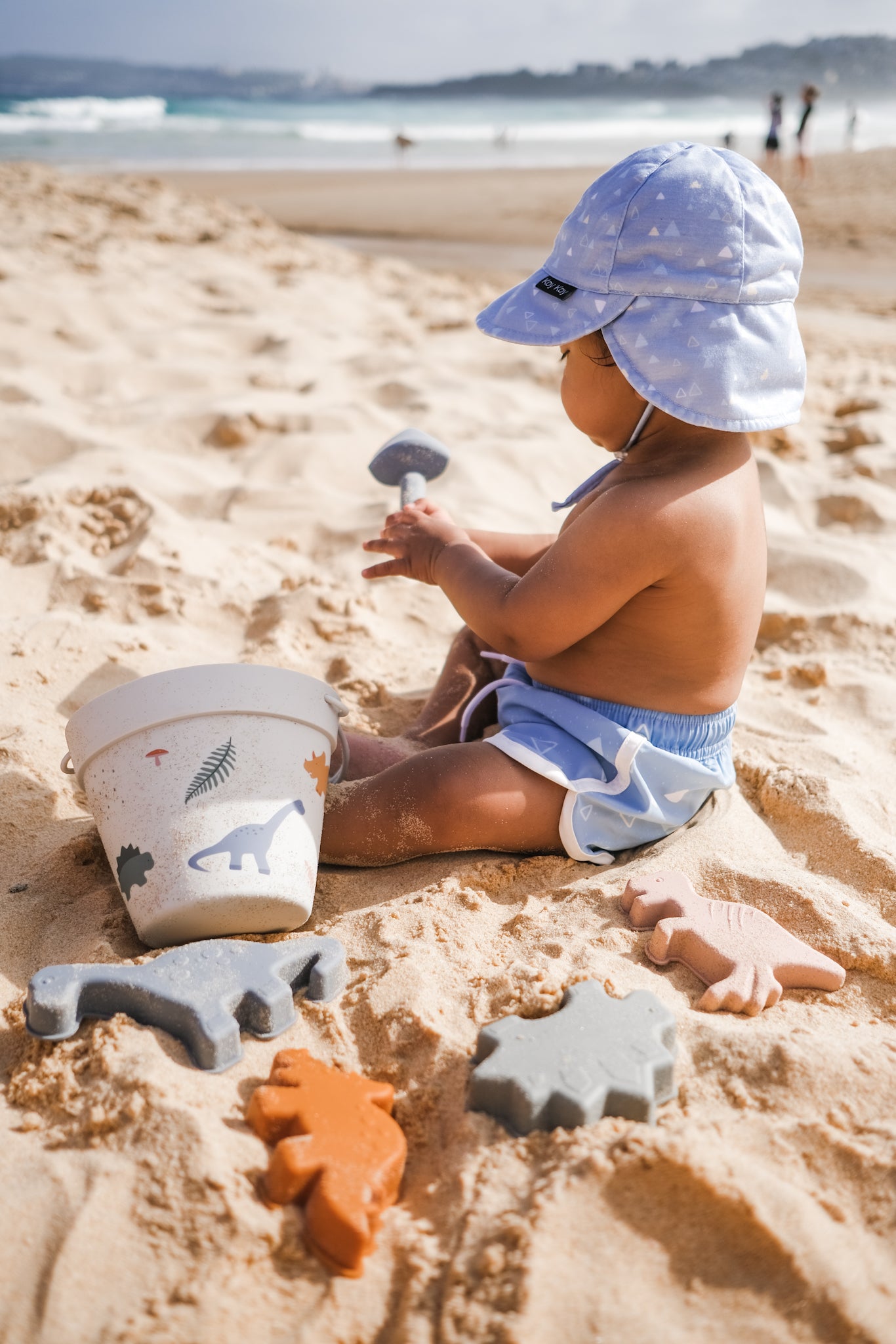 Baby wearing blue boardshorts at the beach