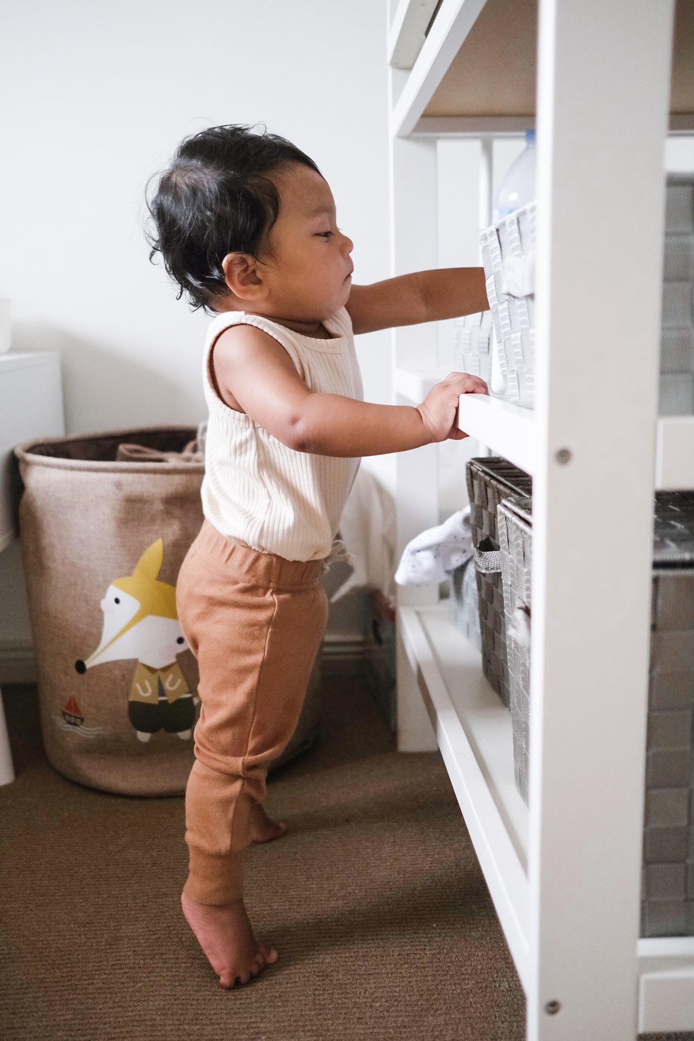 Baby wearing brown leggings reaching over 