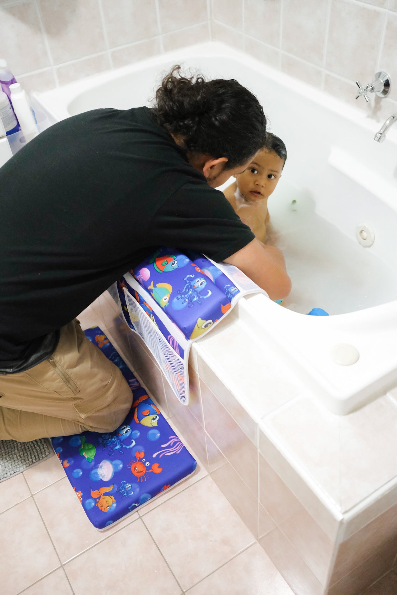 Father giving his son a bath while using baby kneeler and elbow pads to protect his knee and elbows 