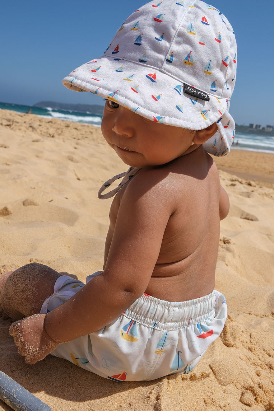 Baby wearing boardshorts at the beach